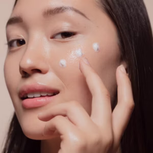 A woman with sensitive skin gently applying mineral sunscreen to her face